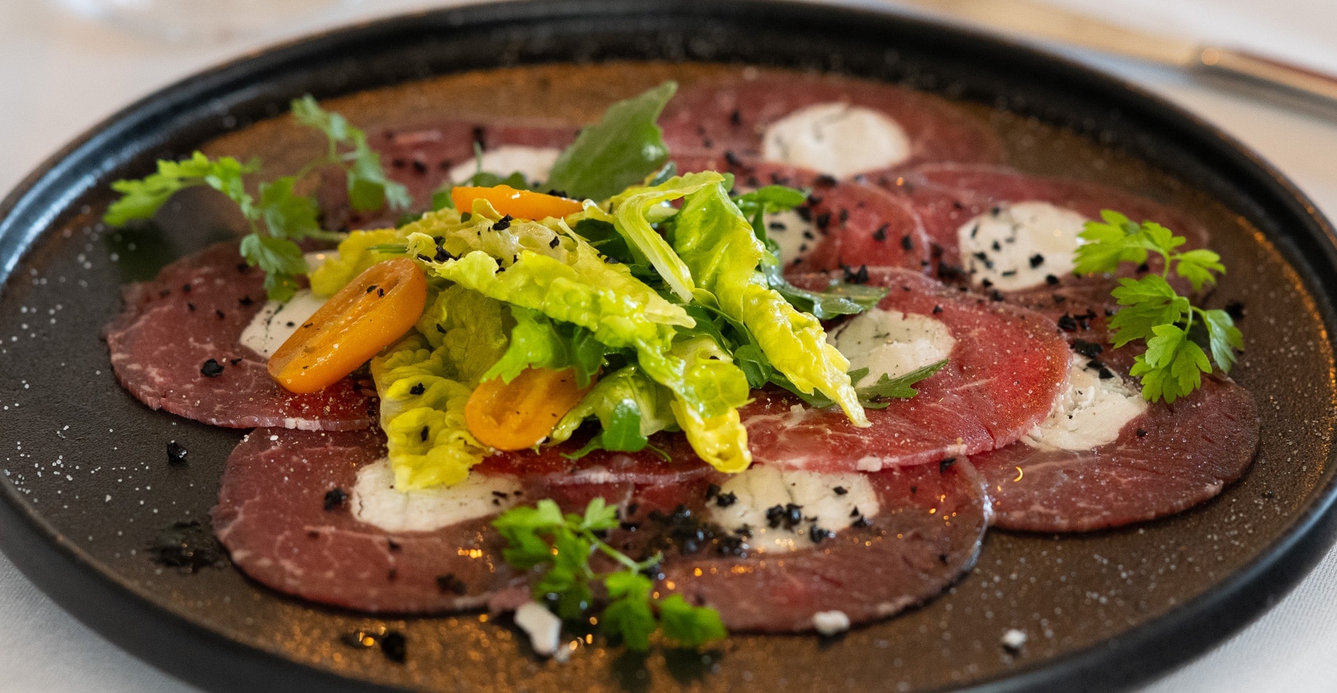 Rindercarpaccio angerichtet auf einem Teller mit Salat.
